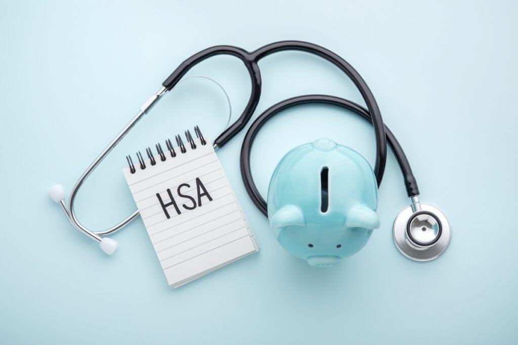 Health Savings Account (HSA) written on notepad with piggy banks