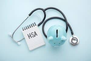 Health Savings Account (HSA) written on notepad with piggy banks