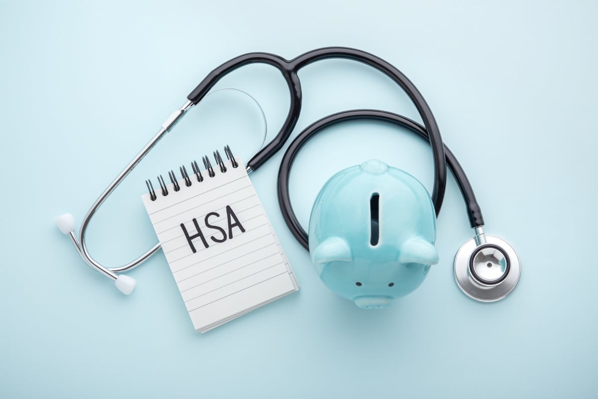 Health Savings Account (HSA) written on notepad with piggy banks